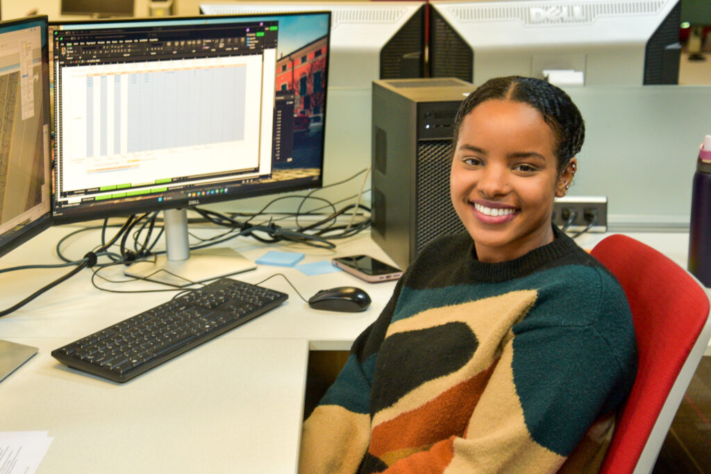 Ahlaam smiling at her desk during her internship.